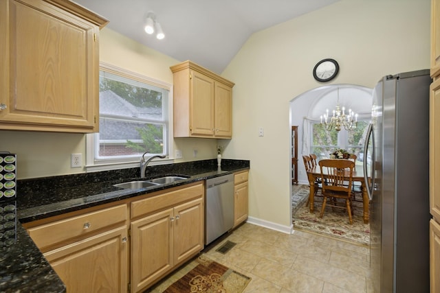 kitchen featuring sink, lofted ceiling, light brown cabinets, dark stone countertops, and appliances with stainless steel finishes