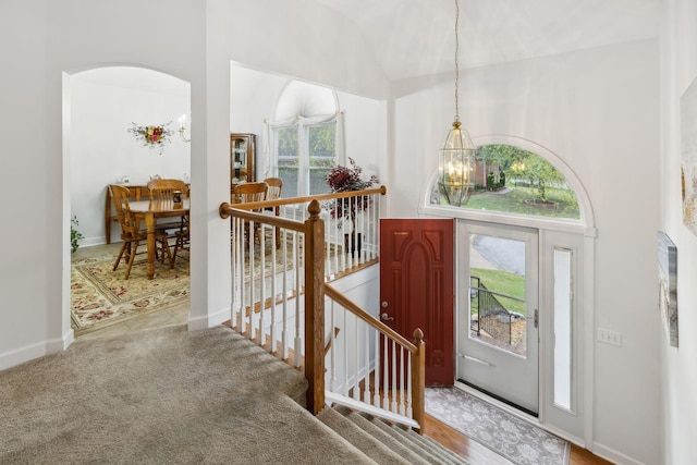 carpeted foyer entrance featuring an inviting chandelier and plenty of natural light