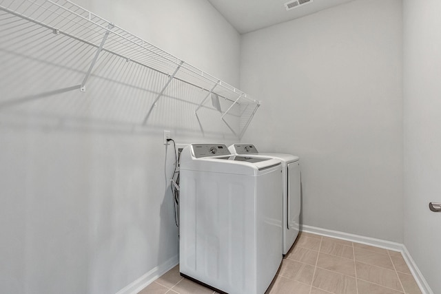 laundry area with independent washer and dryer and light tile patterned floors