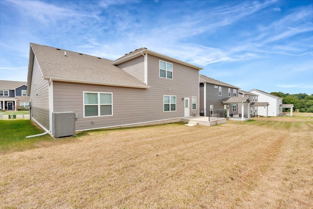 back of property featuring central air condition unit and a lawn