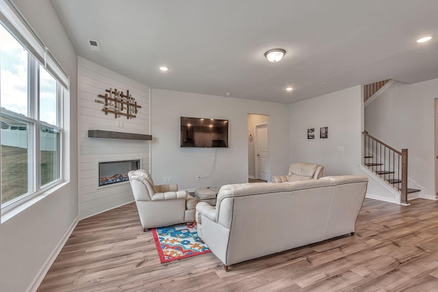 living room with a fireplace, light wood-type flooring, and a wealth of natural light