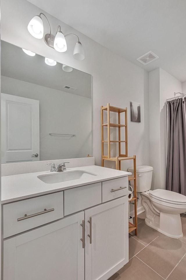 bathroom featuring toilet, tile patterned flooring, walk in shower, and vanity