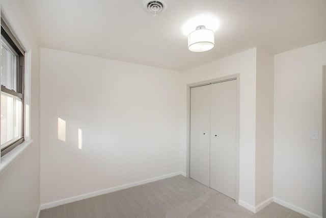 unfurnished bedroom featuring a closet and light carpet