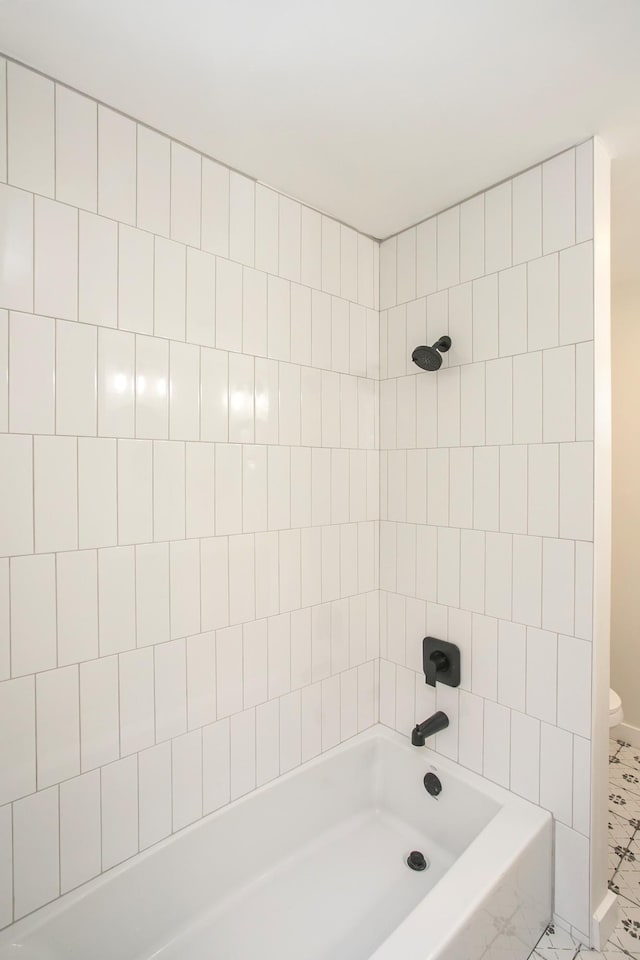 bathroom featuring toilet and tiled shower / bath