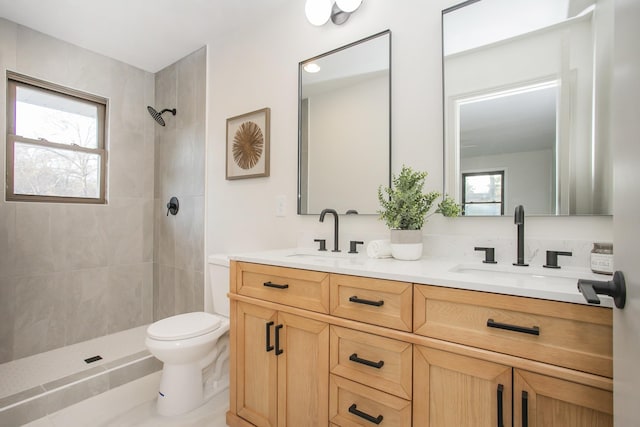 bathroom featuring a tile shower, vanity, and toilet