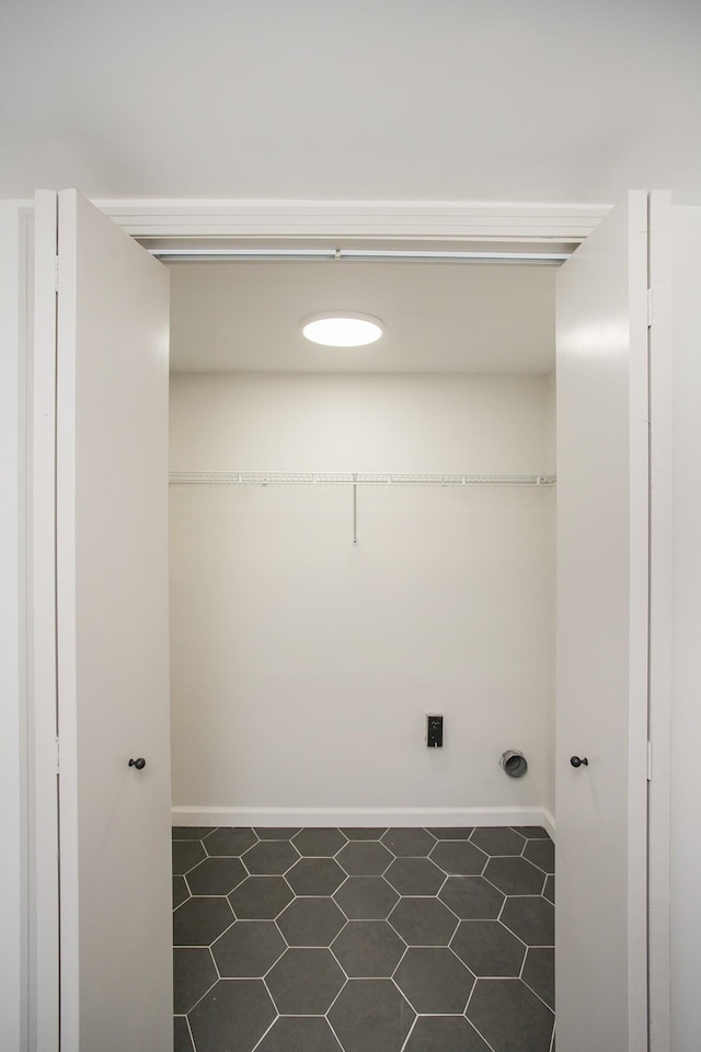 clothes washing area with dark tile patterned floors