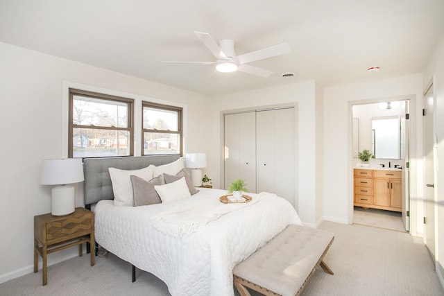 bedroom with ensuite bathroom, light carpet, a closet, and ceiling fan