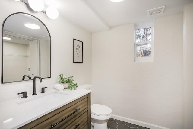 bathroom with toilet, vanity, and tile patterned floors