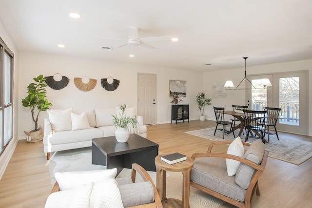 living room featuring ceiling fan with notable chandelier and light hardwood / wood-style floors