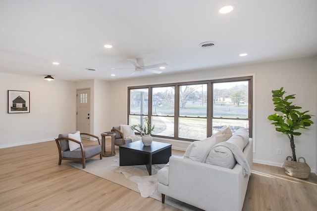 living room featuring ceiling fan, light hardwood / wood-style flooring, and a wealth of natural light