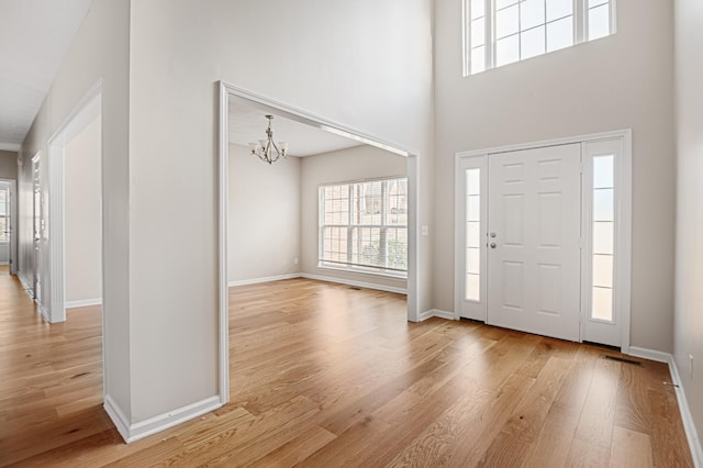 foyer with a towering ceiling, a chandelier, and light hardwood / wood-style flooring