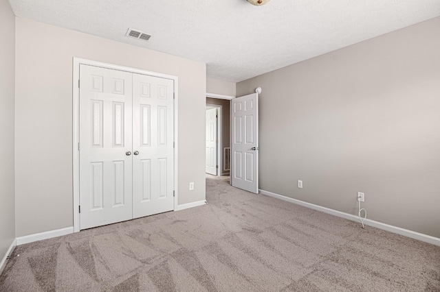 unfurnished bedroom with a closet and light colored carpet