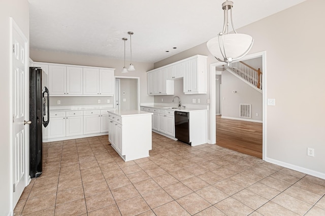 kitchen featuring decorative light fixtures, a center island, black appliances, and white cabinets