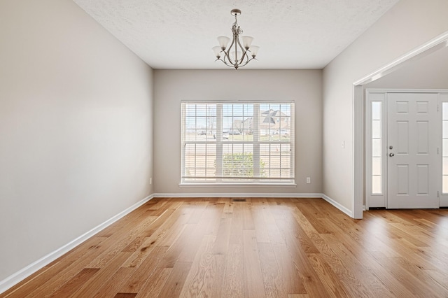 foyer featuring a textured ceiling, light hardwood / wood-style floors, and an inviting chandelier