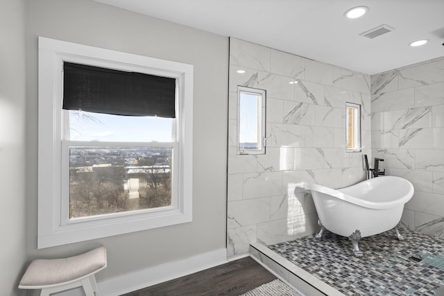 bathroom with a tub, plenty of natural light, and hardwood / wood-style flooring