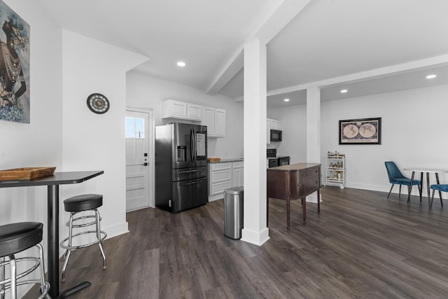 kitchen with black appliances, beamed ceiling, dark hardwood / wood-style flooring, a breakfast bar, and white cabinetry