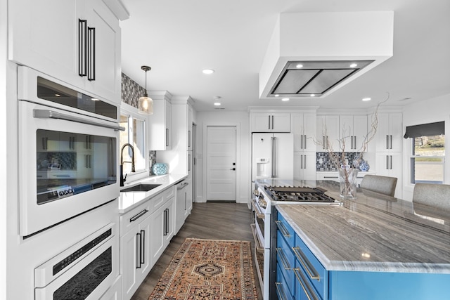 kitchen featuring blue cabinetry, light stone counters, white cabinets, sink, and premium appliances