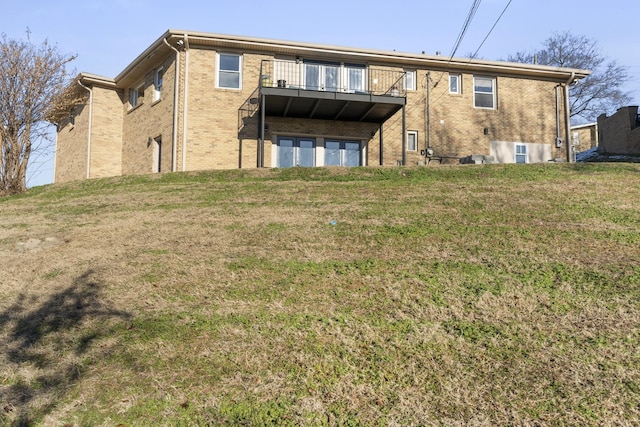 back of property featuring a balcony and a lawn