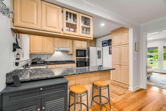 kitchen with a breakfast bar area, black appliances, crown molding, kitchen peninsula, and tasteful backsplash