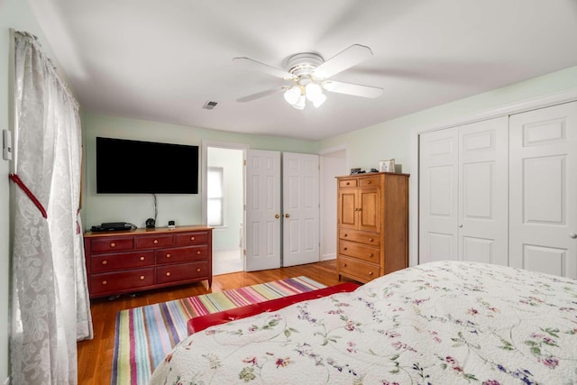 bedroom with ceiling fan, connected bathroom, a closet, and hardwood / wood-style flooring