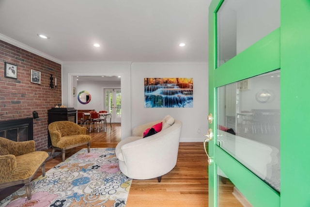 living room with brick wall, light wood-type flooring, crown molding, and a fireplace