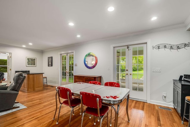 dining space featuring ornamental molding, light wood-type flooring, french doors, and plenty of natural light