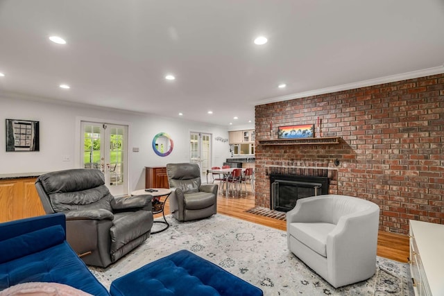 living room featuring ornamental molding, french doors, light hardwood / wood-style floors, and a fireplace