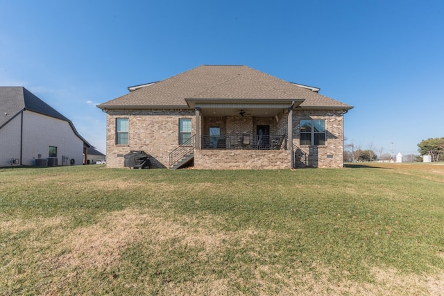 rear view of house with central AC unit and a yard