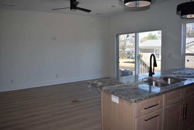 kitchen with sink, dark stone countertops, dark hardwood / wood-style flooring, and ceiling fan