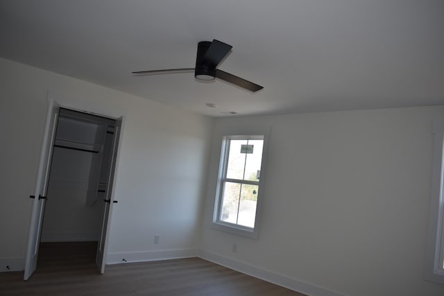 unfurnished bedroom with a closet, ceiling fan, hardwood / wood-style flooring, and a spacious closet