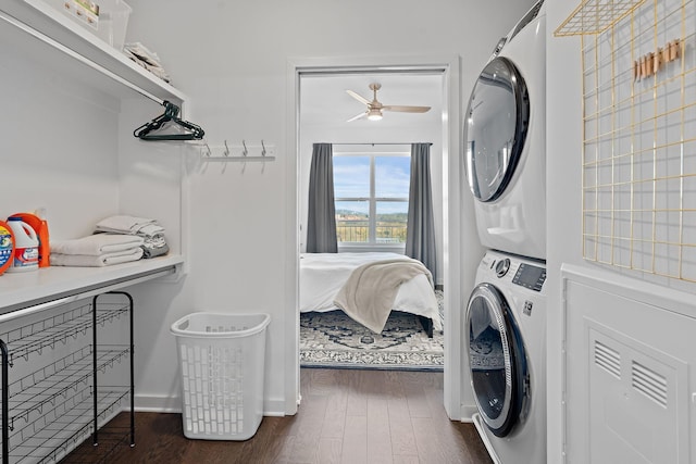 clothes washing area with stacked washing maching and dryer, ceiling fan, and dark wood-type flooring