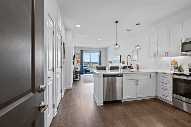 kitchen with stainless steel appliances, white cabinets, sink, and kitchen peninsula