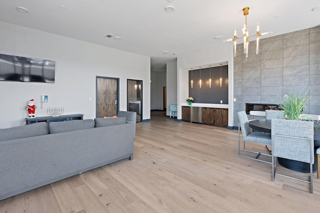 living room featuring tile walls, a fireplace, light hardwood / wood-style floors, and a chandelier