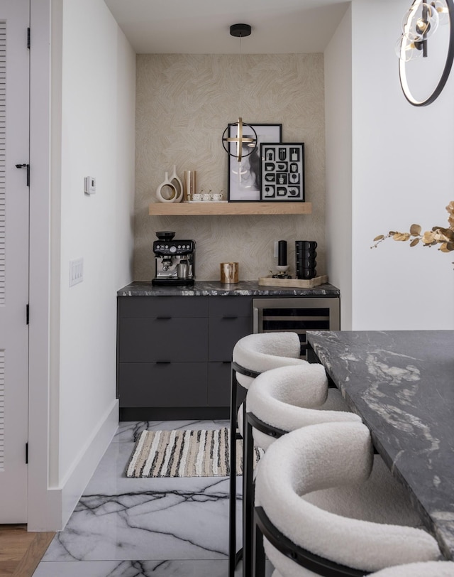 bar with dark stone countertops, pendant lighting, gray cabinetry, and wine cooler