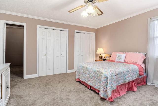 carpeted bedroom with ceiling fan, ornamental molding, and multiple closets