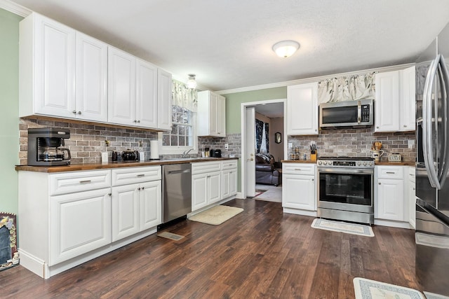 kitchen with dark wood-type flooring, stainless steel appliances, backsplash, white cabinetry, and sink