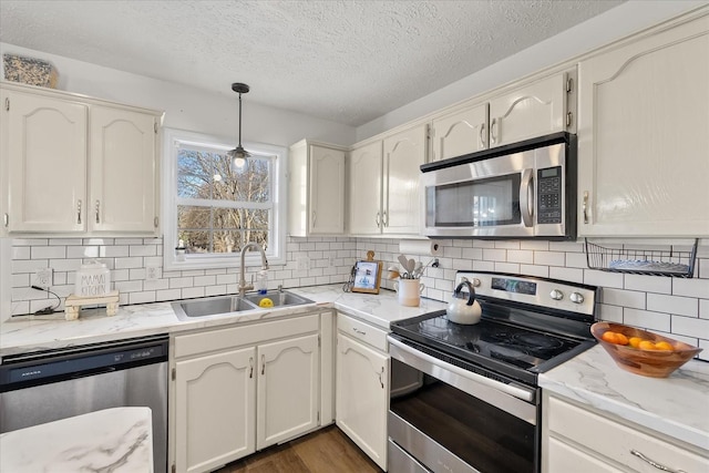 kitchen featuring decorative light fixtures, sink, stainless steel appliances, and white cabinetry