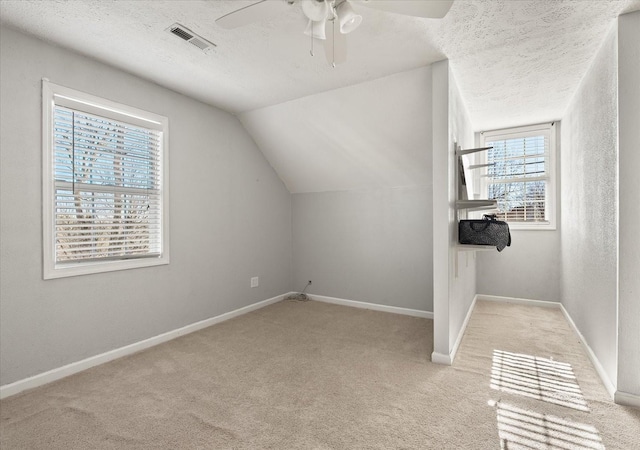 bonus room with light carpet, ceiling fan, lofted ceiling, and a textured ceiling