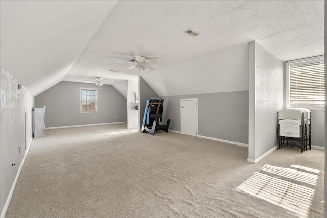 bonus room featuring ceiling fan, light colored carpet, a textured ceiling, and vaulted ceiling