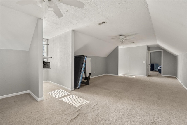 bonus room with ceiling fan, light colored carpet, a textured ceiling, and vaulted ceiling