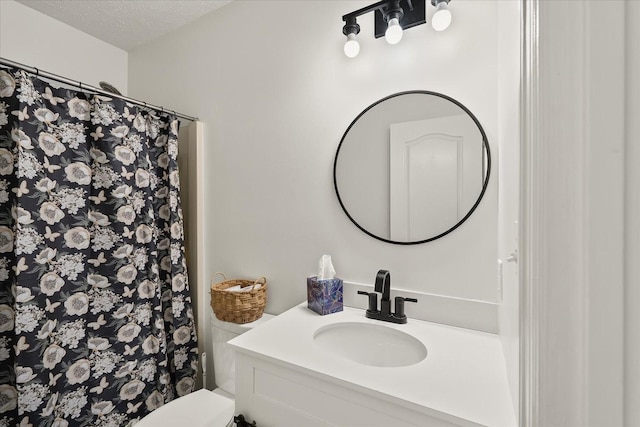 bathroom featuring a textured ceiling, toilet, vanity, and walk in shower