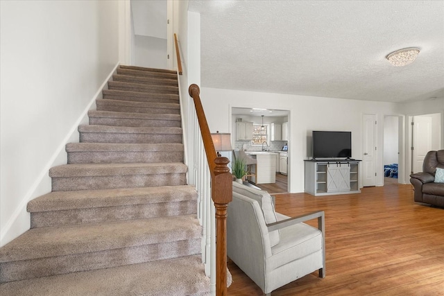 stairs featuring a textured ceiling, hardwood / wood-style floors, and sink