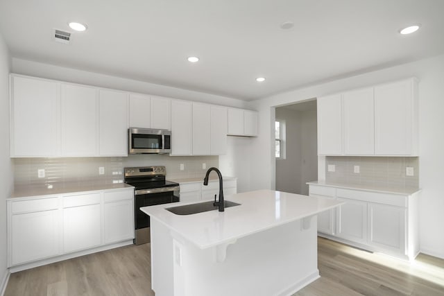 kitchen with white cabinets, a center island with sink, appliances with stainless steel finishes, and sink