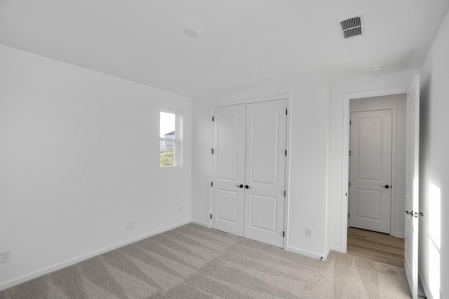 unfurnished bedroom featuring a closet and light carpet