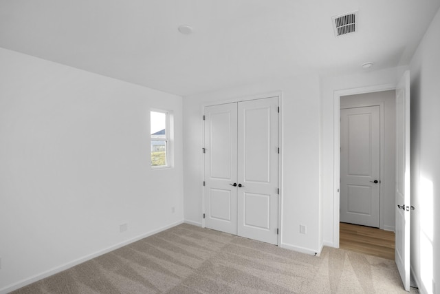 unfurnished bedroom featuring a closet and light carpet