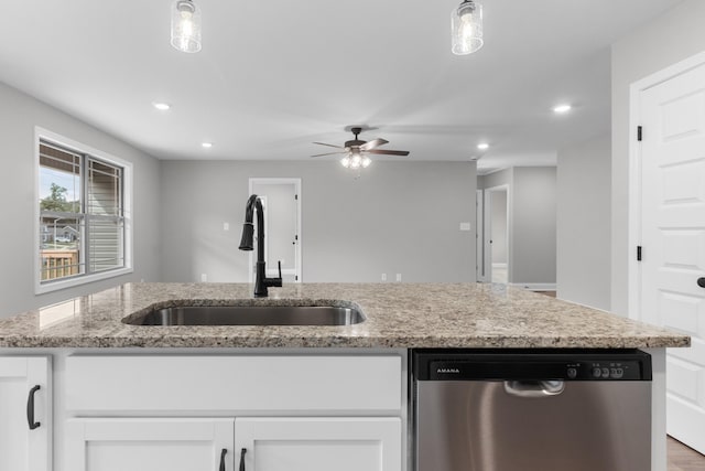 kitchen with white cabinets, light stone counters, sink, decorative light fixtures, and stainless steel dishwasher