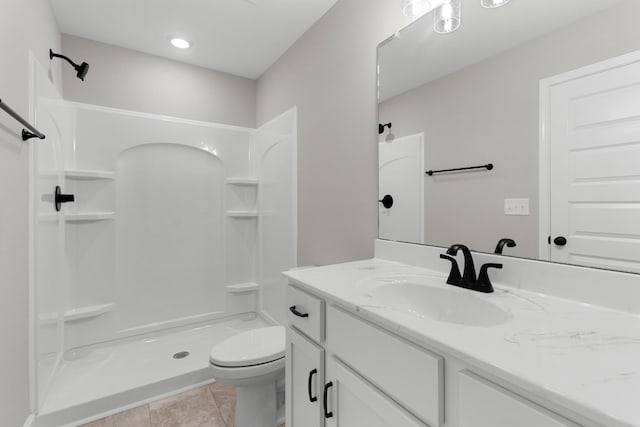 bathroom featuring toilet, tile patterned floors, walk in shower, and vanity