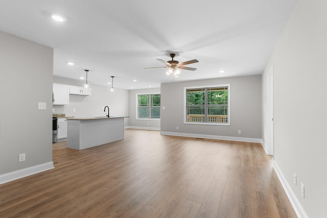 unfurnished living room featuring ceiling fan, light hardwood / wood-style flooring, and sink