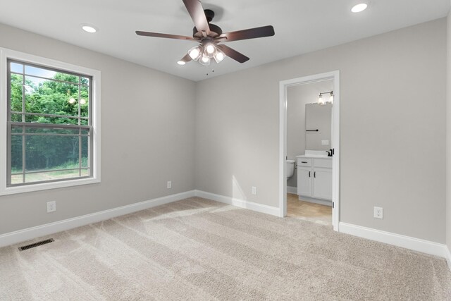 unfurnished bedroom with ceiling fan, light carpet, and ensuite bath