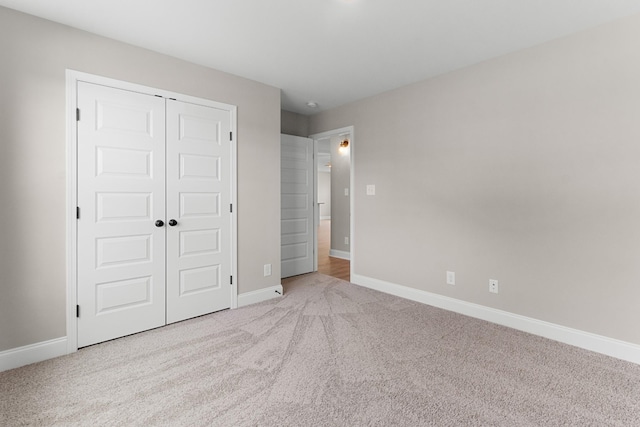 unfurnished bedroom featuring light colored carpet and a closet